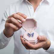 Person holding a pink jewelry box with a butterfly necklace inside