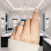 Hand wearing a diamond ring on a white background