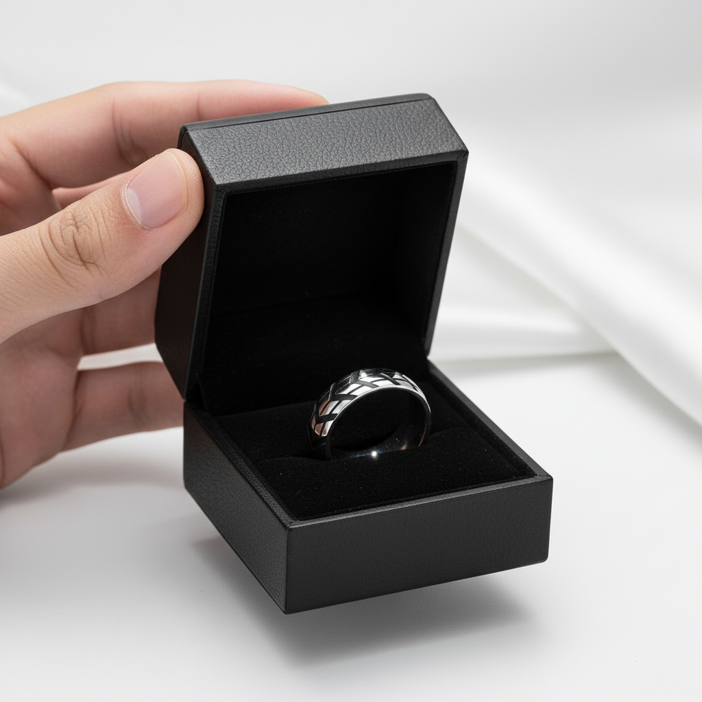 Hand opening a black jewelry box to reveal a silver ring on a light background