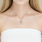 A close-up of a model wearing a delicate silver dreamcatcher necklace with a circular pendant and dangling charms, styled with a white strapless top.