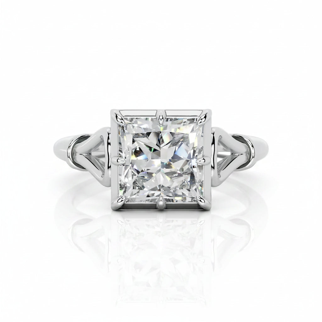 An emerald-cut diamond ring with a silver-toned split-shank band, centered on a reflective white surface.