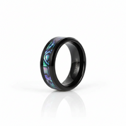 A black titanium ring with an iridescent abalone shell inlay, shown on a clean white background with a soft reflection.