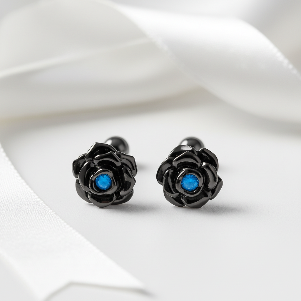 Black rose-shaped cufflinks with blue centers on a white fabric background