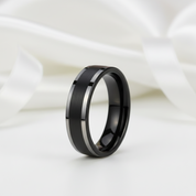 Black ring with a brushed finish on a white fabric background