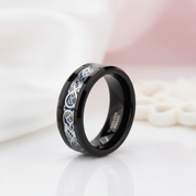 Black tungsten ring with silver Celtic knot design on a white background