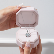 Jewelry box with a diamond necklace held by a hand against a light background
