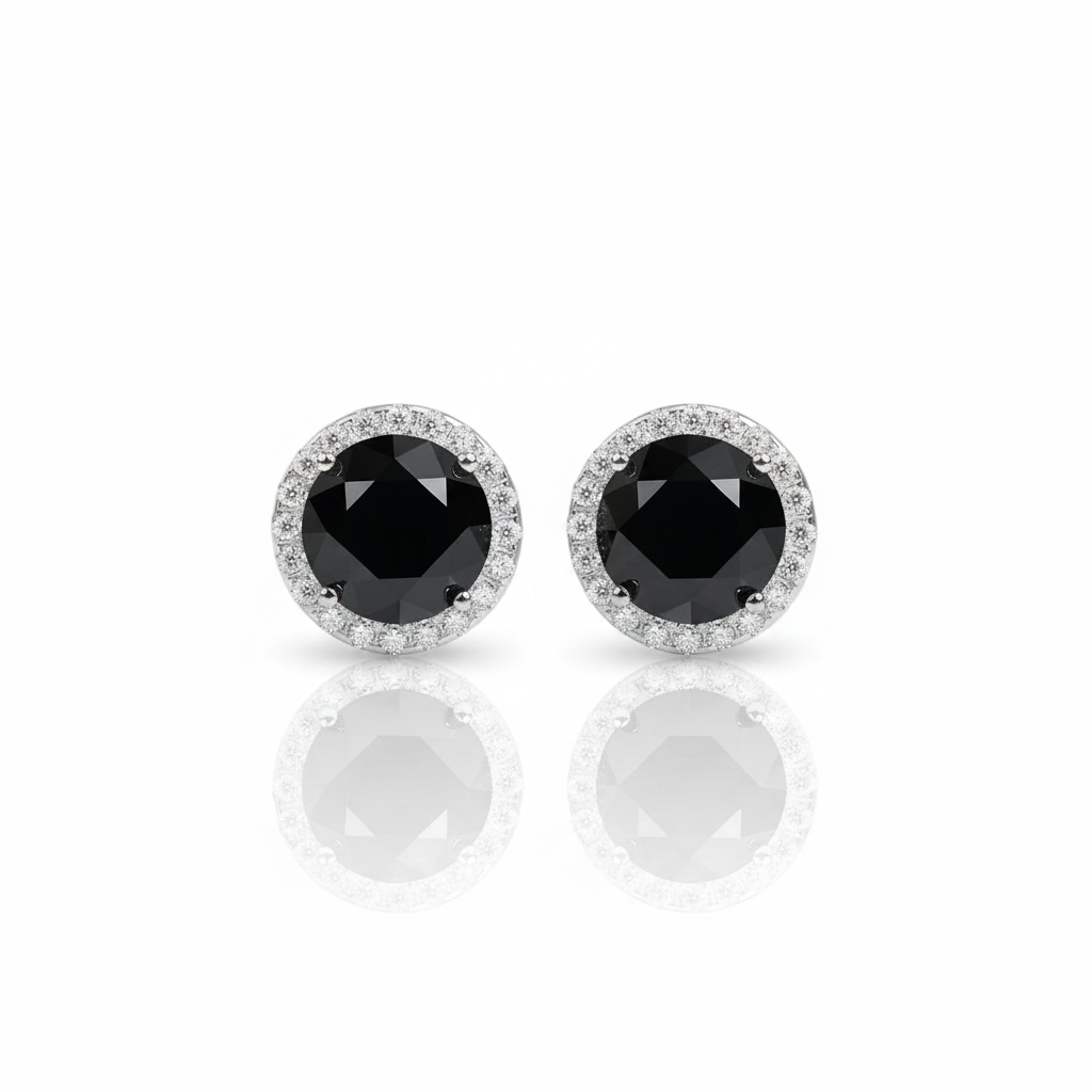 A pair of round stud earrings featuring a central faceted black gemstone surrounded by a halo of small clear stones, set in a silver-toned metal, shown on a white background with a soft reflection below.