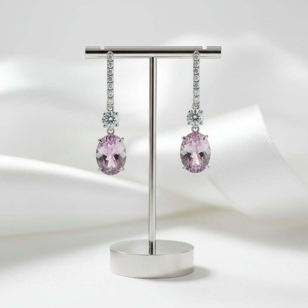 Pair of pink gemstone earrings on a metal stand against a white background
