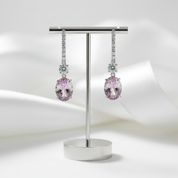 Pair of pink gemstone earrings on a metal stand against a white background