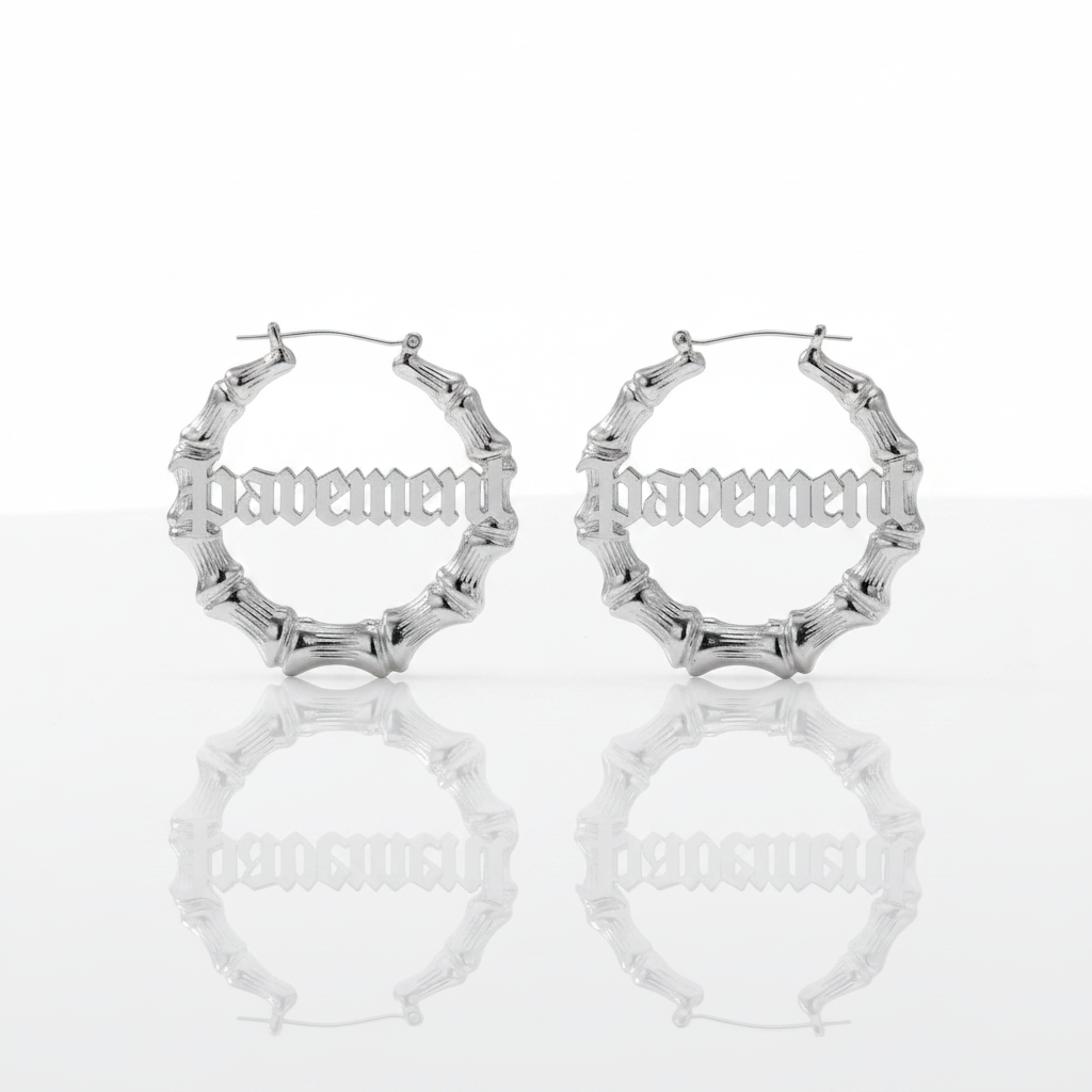 A pair of silver hoop earrings with a textured, segmented outer design and the word 'happiness' in gothic-style lettering across the front, displayed on a reflective white surface against a white background.