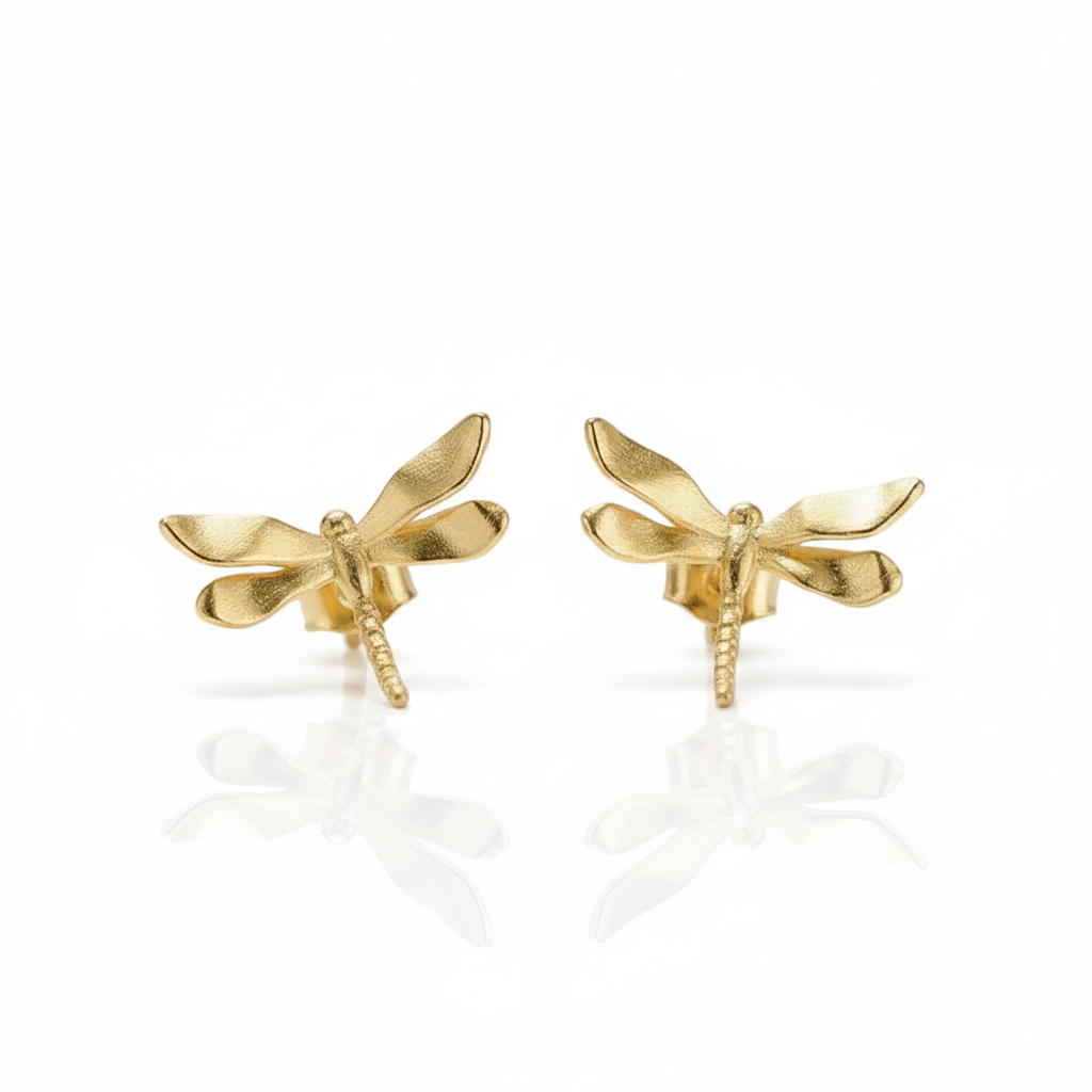 A pair of gold dragonfly stud earrings on a clean white background with soft reflections below.