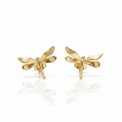A pair of gold dragonfly stud earrings on a clean white background with soft reflections below.