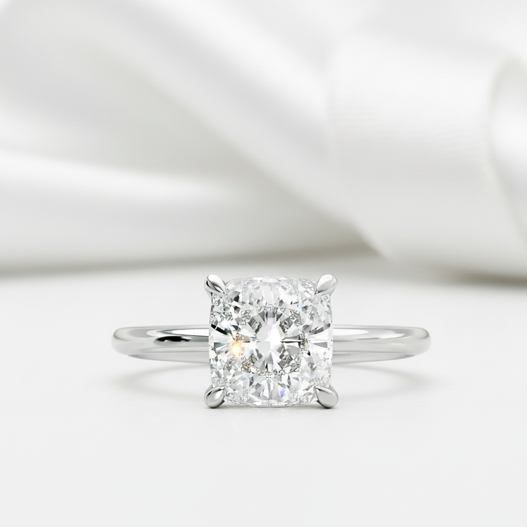 A radiant cut diamond solitaire engagement ring in a four-prong setting on a polished silver band, presented on a soft white background with draped satin fabric.