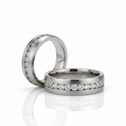 Two polished silver-toned wedding bands with rows of clear round-cut stones, photographed on a clean white reflective surface.