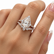 A close-up of a hand wearing a sparkling teardrop-shaped diamond ring in a silver-toned setting with pavé accents on the band, against a clean white background.