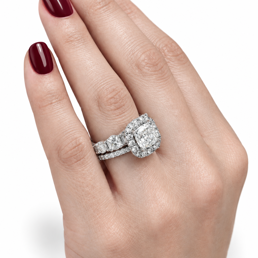 A close-up of a hand wearing a diamond engagement ring with a matching diamond band, set against a clean white background.