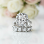Silver ring with diamond accents on a white surface with flowers in the background