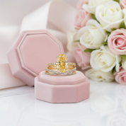 Gold rings on a pink jewelry box with flowers in the background