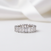 Silver ring with emerald-cut diamonds on a white background