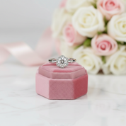 Diamond ring on a pink velvet box with flowers in the background