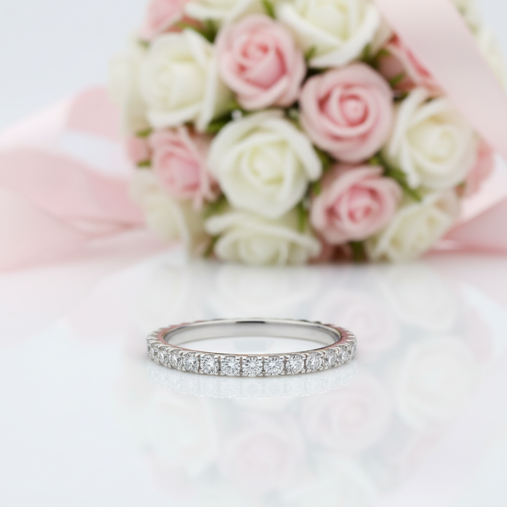 Silver ring with diamonds on a white surface with pink and white roses in the background