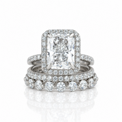 A white gold or platinum engagement ring set featuring a large rectangular emerald-cut diamond surrounded by a halo of smaller round diamonds, with a matching diamond band underneath.