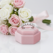 Diamond ring on a pink velvet box with pink and white roses in the background