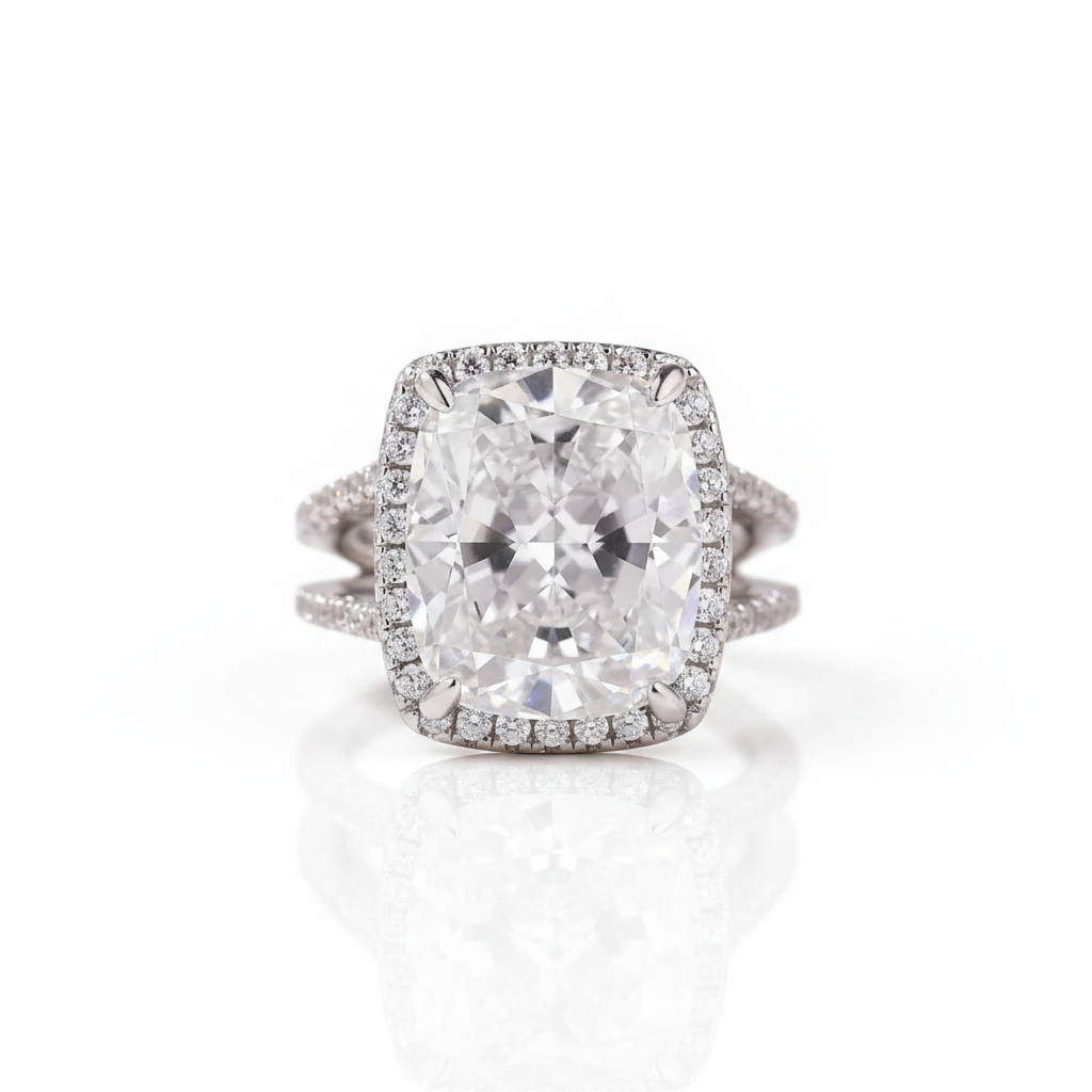 A cushion-cut diamond ring with a halo setting and a split shank band, shown on a clean white background with a soft reflection.