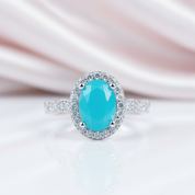 Ring with a turquoise gemstone and diamond accents on a soft pink and white background