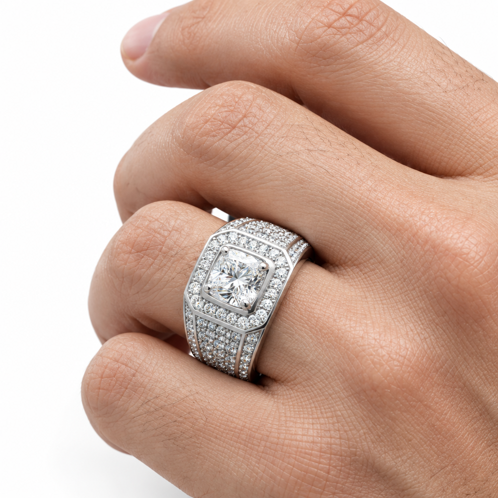 A close-up of a hand wearing a large silver-toned ring with a cushion-cut diamond center and pavé diamond bands, set against a clean white background.