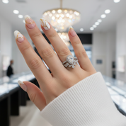 Hand wearing a diamond ring with a blurred jewelry store background
