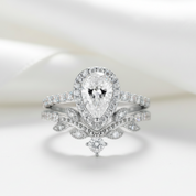 Diamond ring with a pear-shaped center stone on a light background