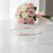 Rose gold bracelet with 'Evan' engraving on a light pink fabric background
