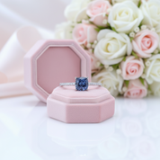 Blue gemstone ring in a pink box with flowers in the background