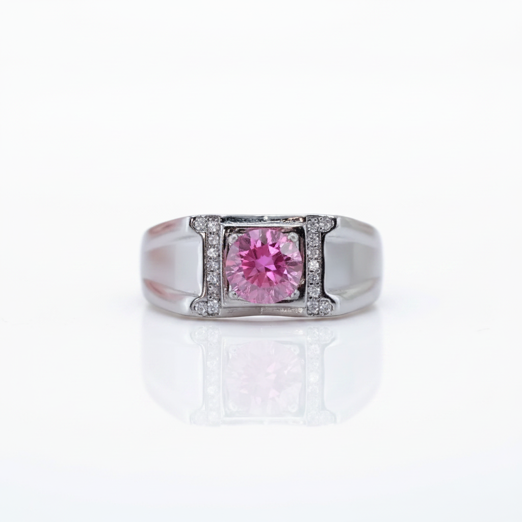 A silver-toned ring featuring a central round pink gemstone surrounded by a double-row border of small clear stones, set against a clean white background with a soft reflection below.