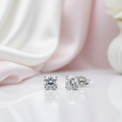 Pair of diamond stud earrings on a soft pink fabric background