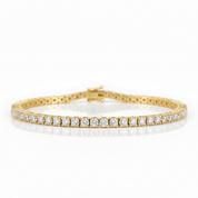 A yellow gold tennis bracelet set with round brilliant-cut diamonds, displayed on a clean white background with a soft reflection.