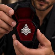 A silver-toned geometric ring with a central marquise-cut diamond and smaller accent diamonds, presented in an open black velvet ring box held by a man.