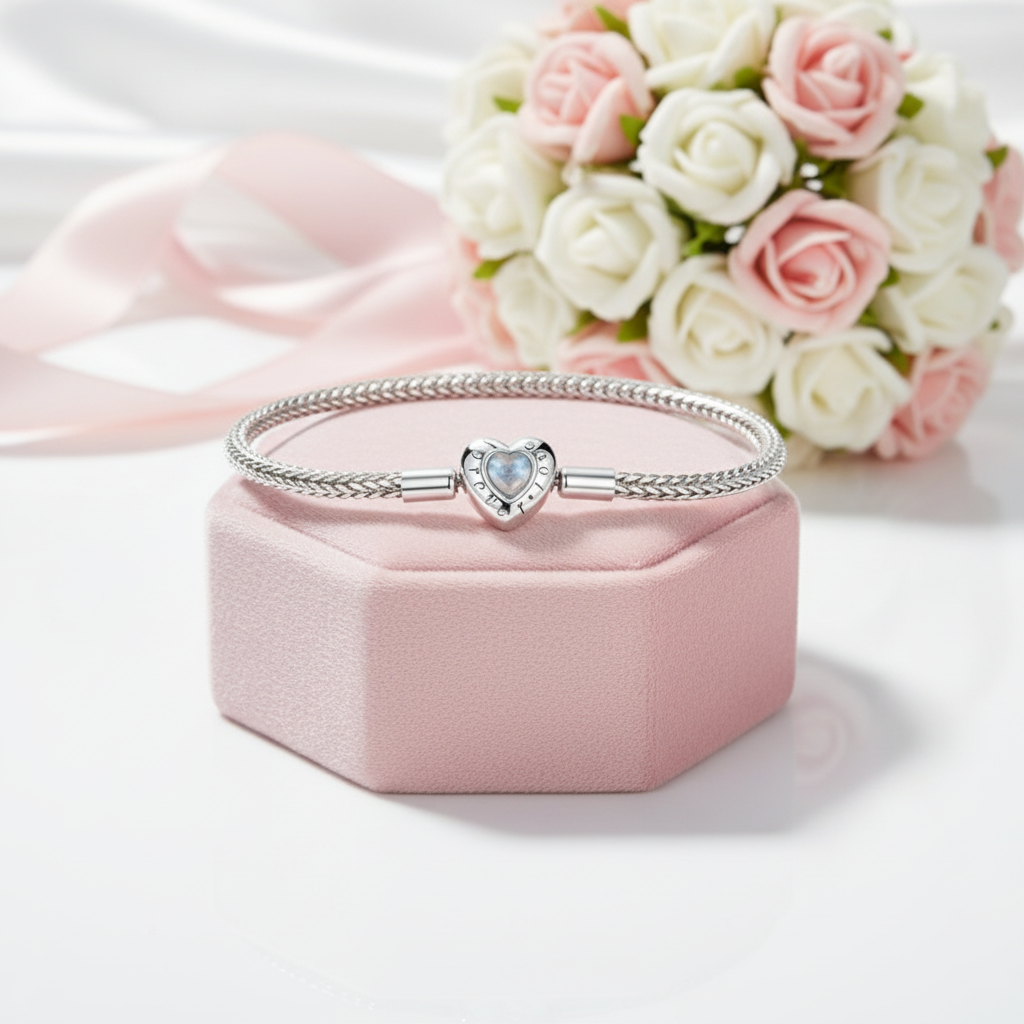Silver bracelet with a heart-shaped charm on a pink jewelry box with flowers in the background