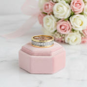 Gold ring with diamonds on a pink jewelry box with flowers in the background