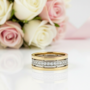 Gold ring with diamonds on a white surface with pink and white roses in the background