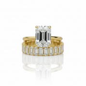 A yellow gold ring set featuring a large emerald-cut clear center stone and a matching row of emerald-cut side stones, shown on a reflective white background.