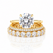 A gold engagement ring with a large round brilliant-cut diamond is displayed with two matching gold wedding bands featuring rows of smaller diamonds on a clean white background with a soft reflection.